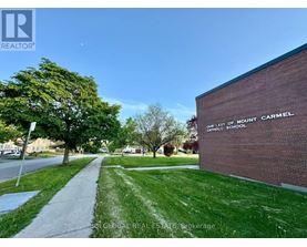 A sidewalk leads to a brick building with a sign that says "Our Lady of Mount Carmel Catholic School.".