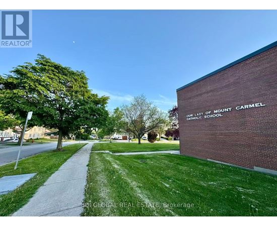 A sidewalk leads to a brick building with a sign that says "Our Lady of Mount Carmel Catholic School.".