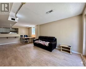 A living room with a black couch and a wooden floor.
