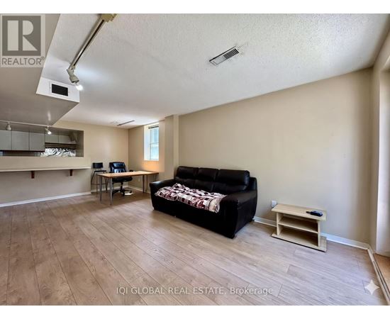 A living room with a black couch and a wooden floor.