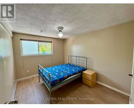 A bedroom with a bed, nightstand, and window.