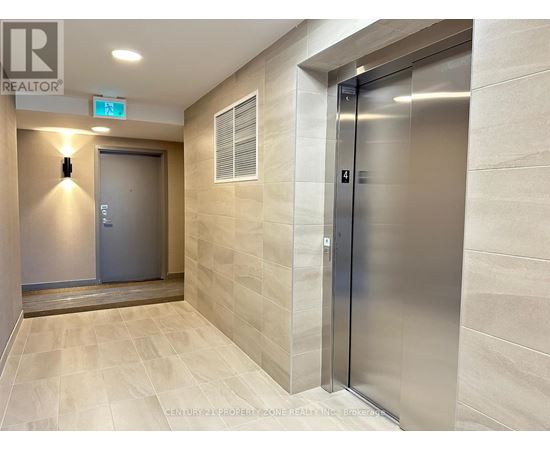 A hallway with a metal elevator and a closed door on the left.