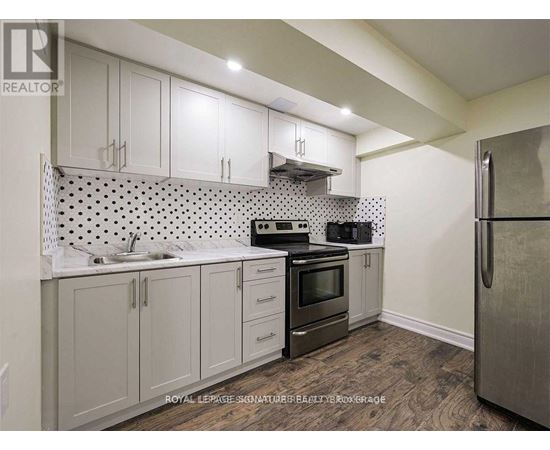 A kitchen with white cabinets and a black and white tiled backsplash.