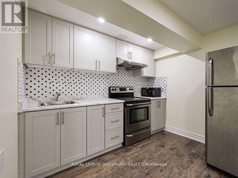 A kitchen with white cabinets and a black and white tiled backsplash.