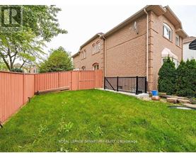 A red brick house with a black gate and a green lawn.