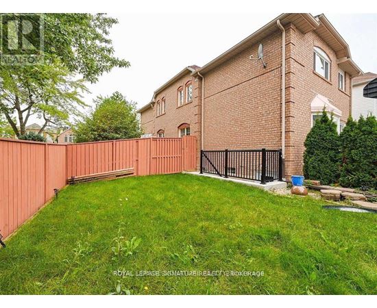 A red brick house with a black gate and a green lawn.