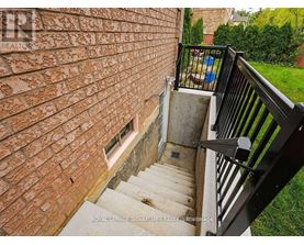 A staircase with a black railing leads up to a brick wall.