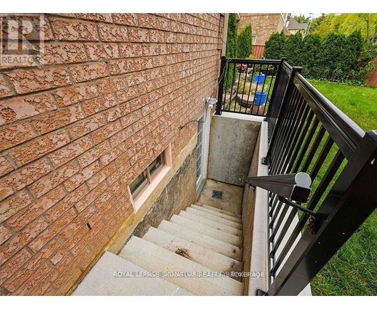 A staircase with a black railing leads up to a brick wall.