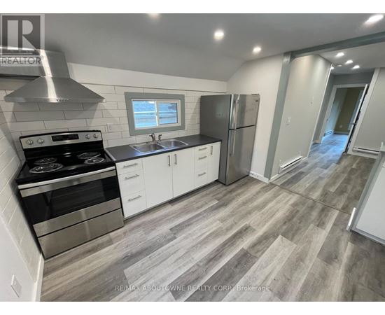 A modern kitchen with a stove top oven, sink, and refrigerator.