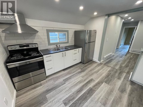 A modern kitchen with a stove top oven, sink, and refrigerator.