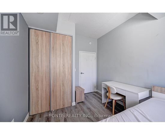 A bedroom with a bed, desk, and wardrobe.
