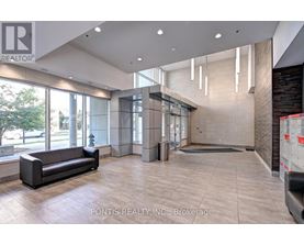 A spacious lobby with a black sofa and a large window.