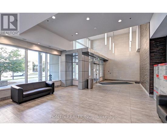 A spacious lobby with a black sofa and a large window.