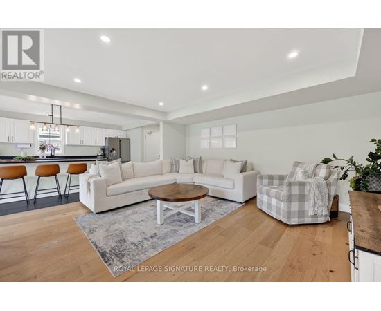 A modern living room with a white sofa set and wooden flooring.