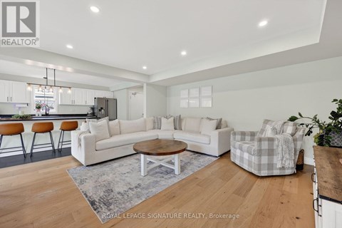 A modern living room with a white sofa set and wooden flooring.
