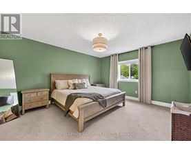 A bedroom with a bed, nightstand, and window.