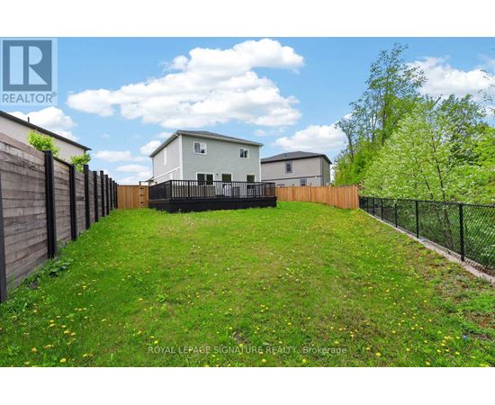 A grassy backyard with a fence and a house in the background.