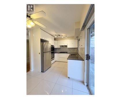 A modern kitchen with white cabinets and a stainless steel refrigerator.