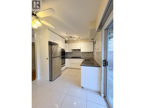 A modern kitchen with white cabinets and a stainless steel refrigerator.