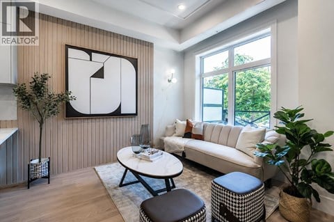 A living room with a white couch, a coffee table, and a large abstract painting on the wall.