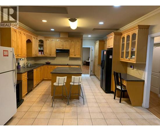 A kitchen with wooden cabinets and a black refrigerator.