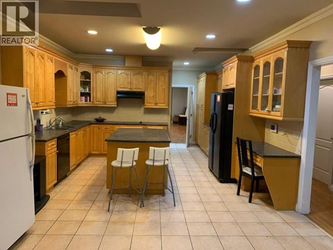 A kitchen with wooden cabinets and a black refrigerator.