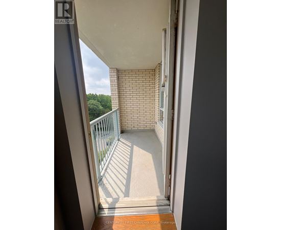 A balcony with a white railing and a view of trees.