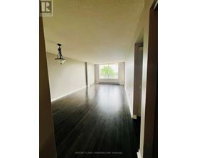 A long hallway with wood floors and a light on the ceiling.