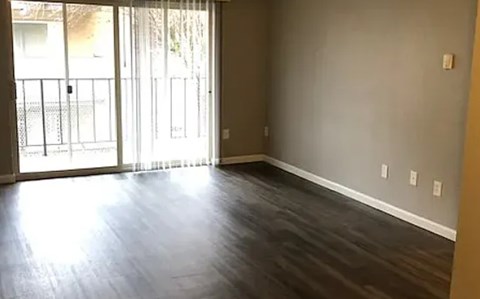 A room with a sliding glass door and wood flooring.