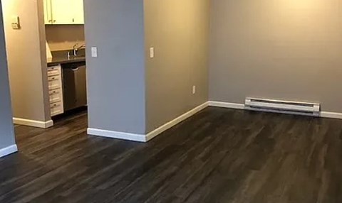A room with a dark wood floor and a white wall.