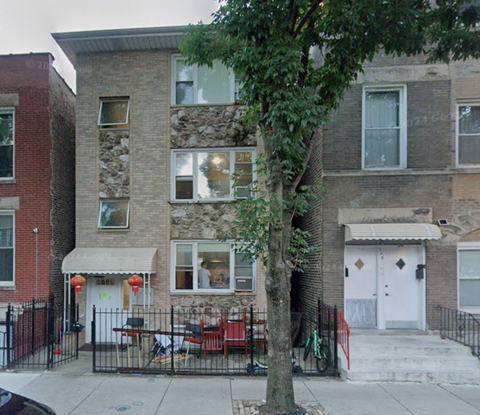 A tree in front of a building with a white door.