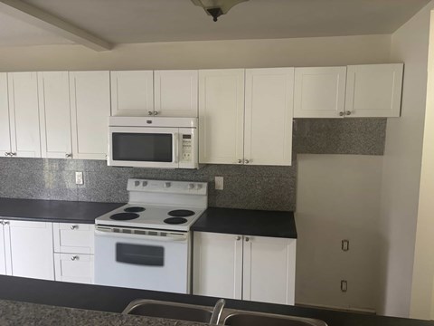 A kitchen with white cabinets and a black countertop.