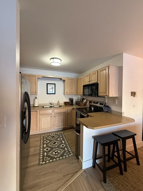 A kitchen with wooden cabinets and a black fridge.