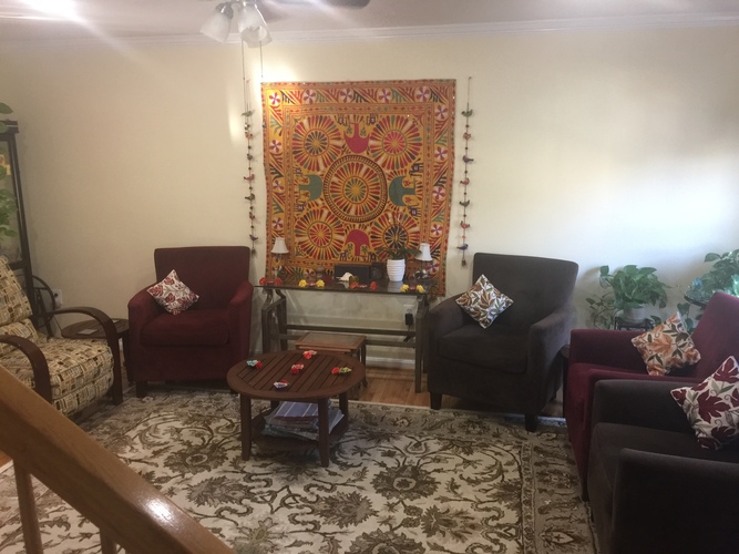 A living room with a large tapestry hanging on the wall and a rug on the floor.