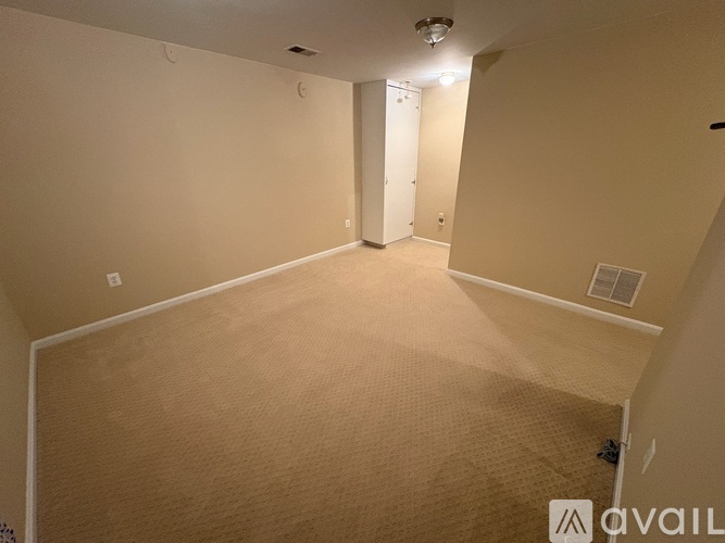 A spacious room with beige carpeting and white walls.