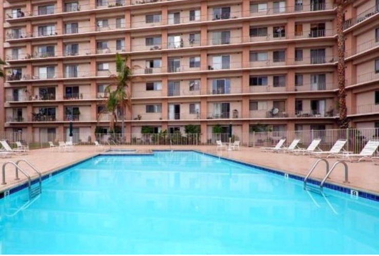 A large swimming pool in front of a multi-story apartment building.
