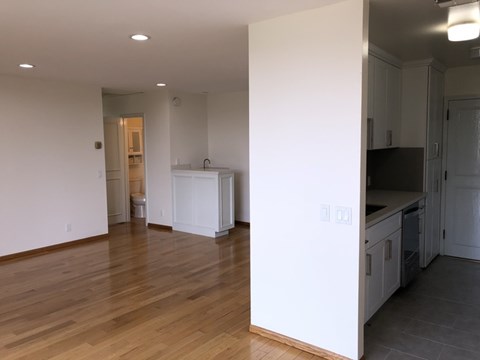 A kitchen with white cabinets and a wooden floor.