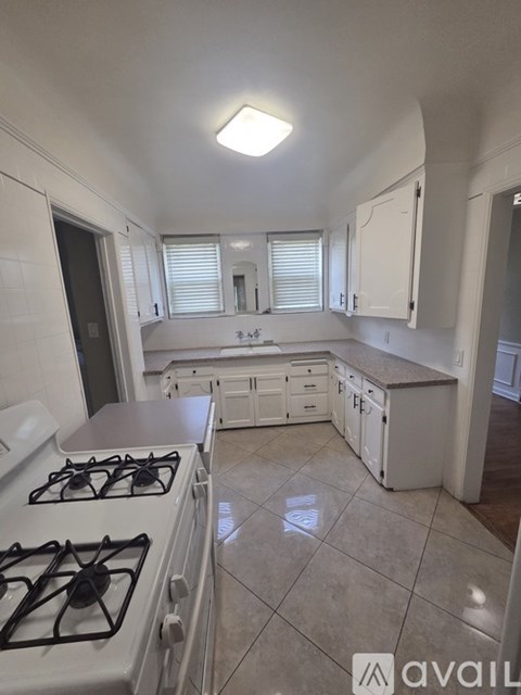 A kitchen with a white stove and white cabinets.