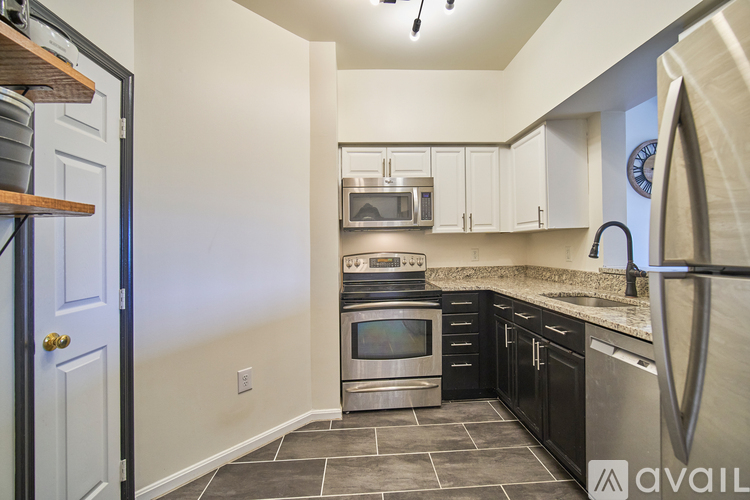 A kitchen with black cabinets and a stainless steel refrigerator.