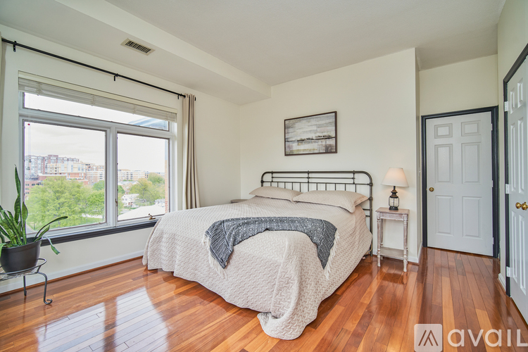 A bedroom with a large bed and a window overlooking a cityscape.