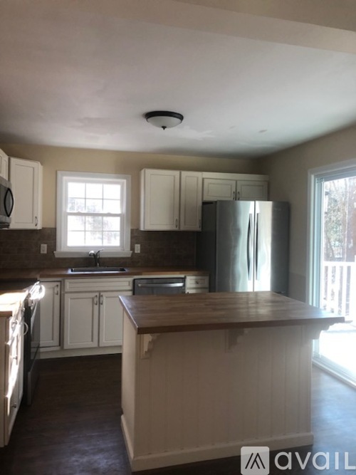 A kitchen with white cabinets and a wooden island.