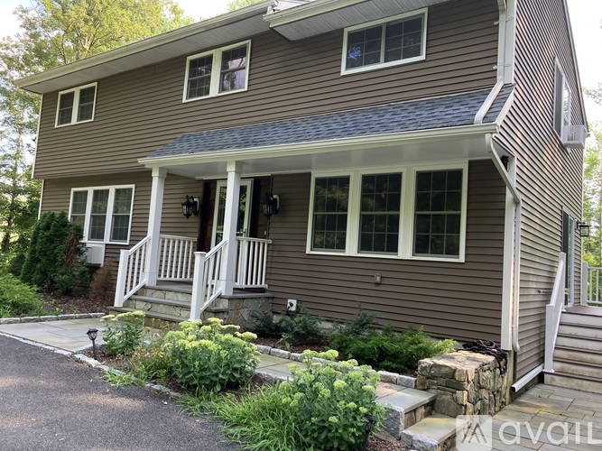 A house with a brown siding and a white porch.