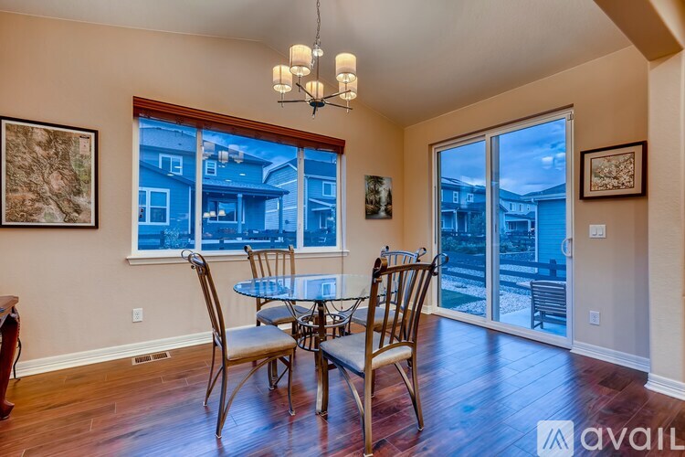 A dining room with a table and chairs and a view of the outside.