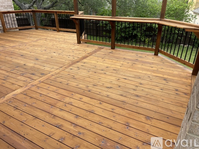 A wooden deck with a railing and trees in the background.