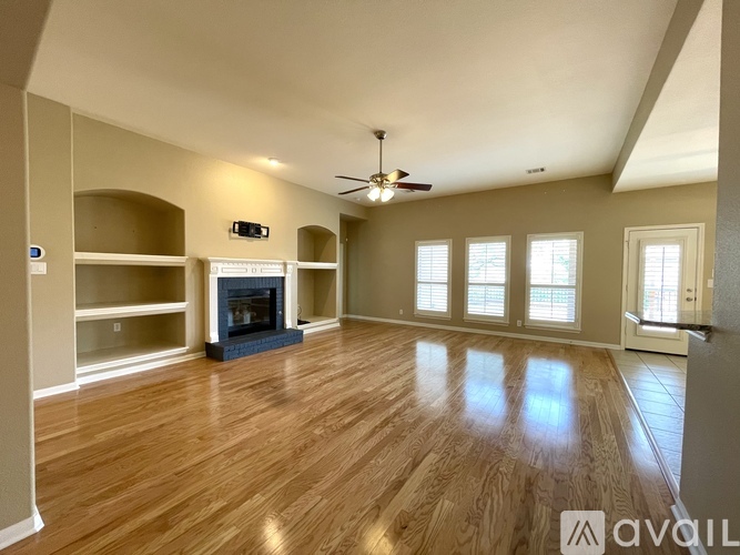 A spacious room with wooden floors and a fireplace.