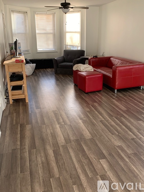 A living room with a red couch and a wooden floor.