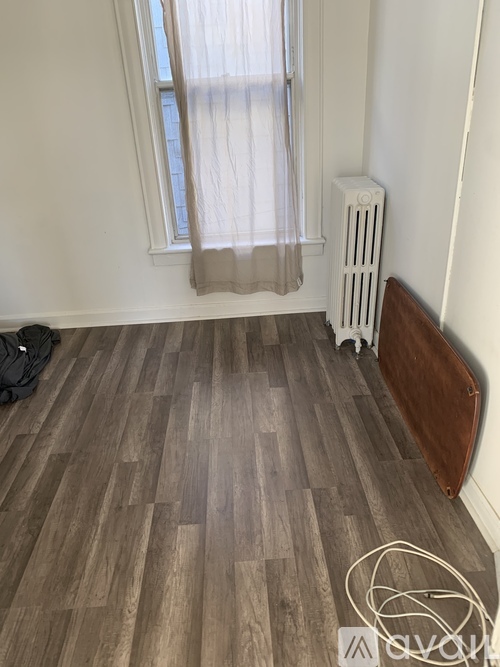 A room with a window and a radiator on the floor.