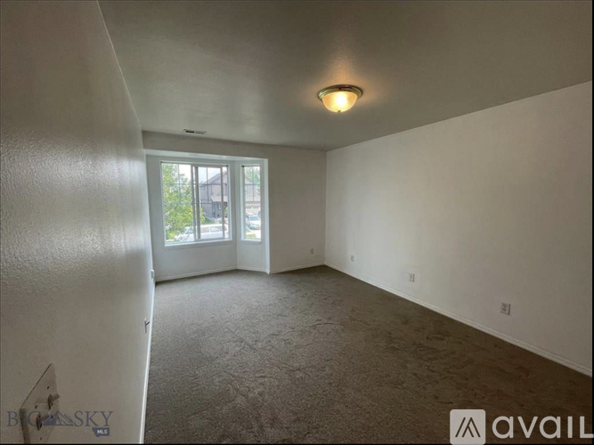 A spacious room with a carpeted floor and a window with blinds.