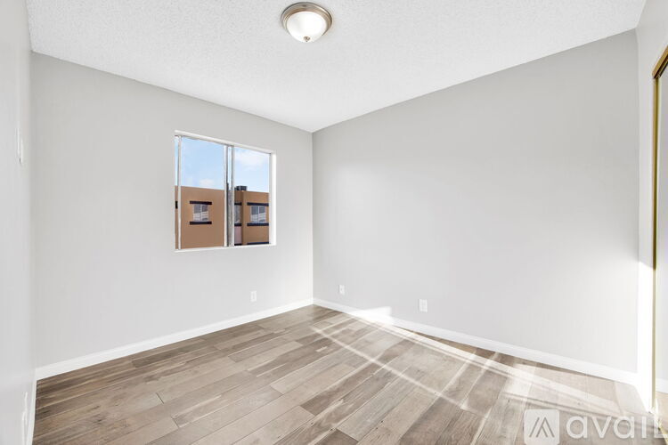 A room with a wooden floor and a window showing a view of buildings outside.