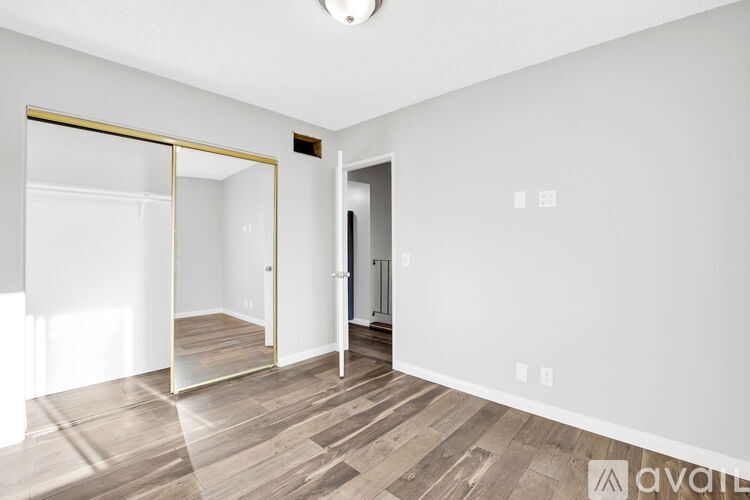 A spacious room with a wooden floor and a large mirror on the wall.
